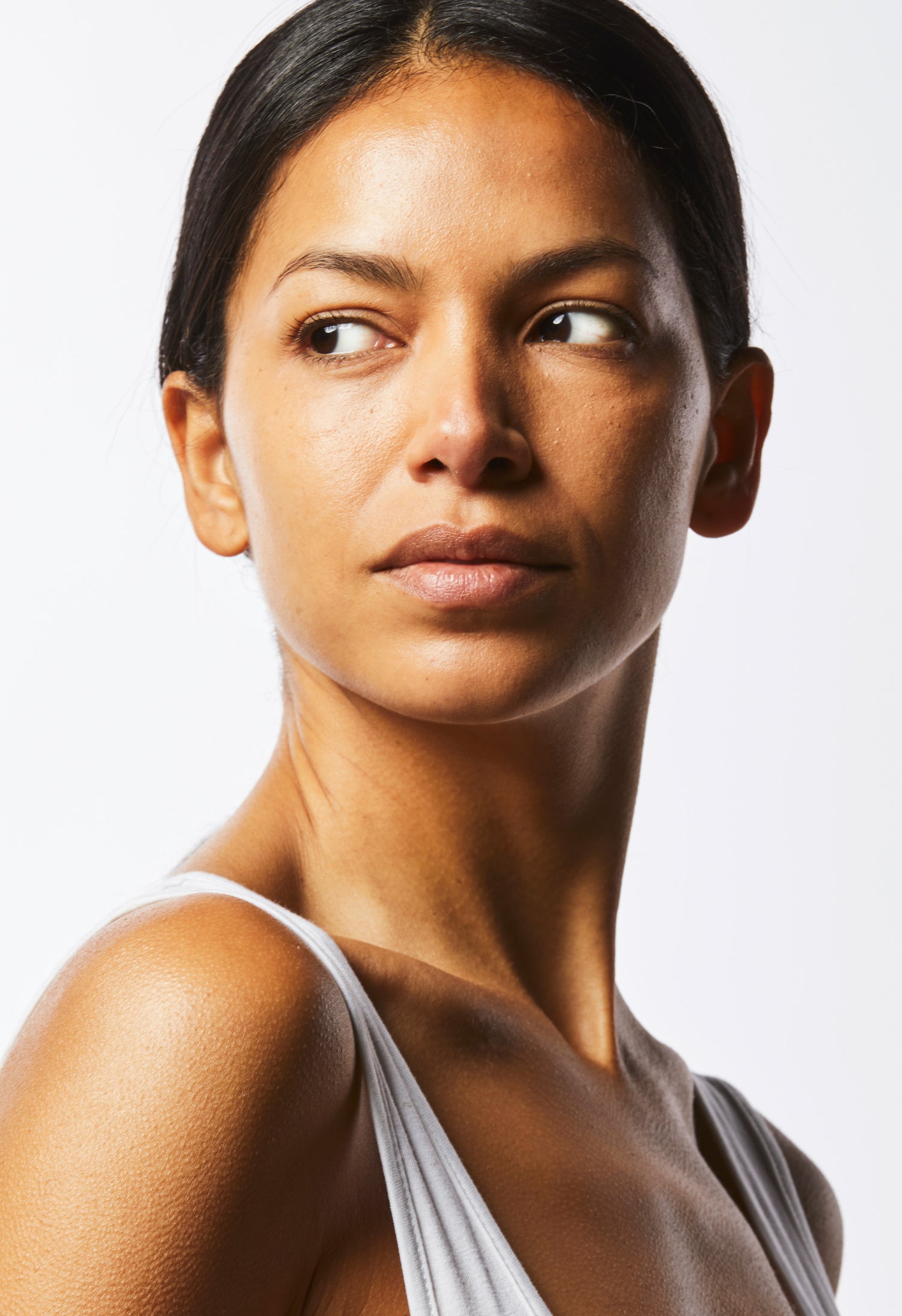 A shoulders up image of a model with clear, glowing skin looking to the side.