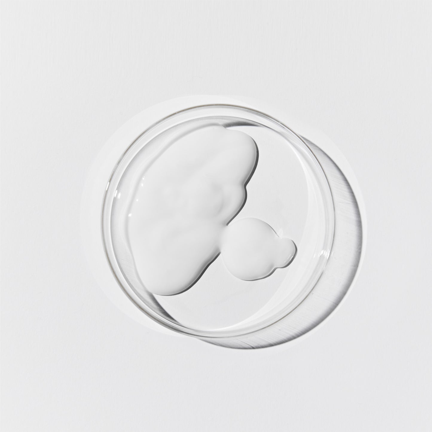 Aerial shot of the cleansing milk. It's an opaque, white liquid in a petri dish against a white background.